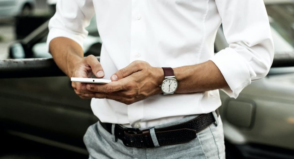 a man in a white shirt is holding a smartphone